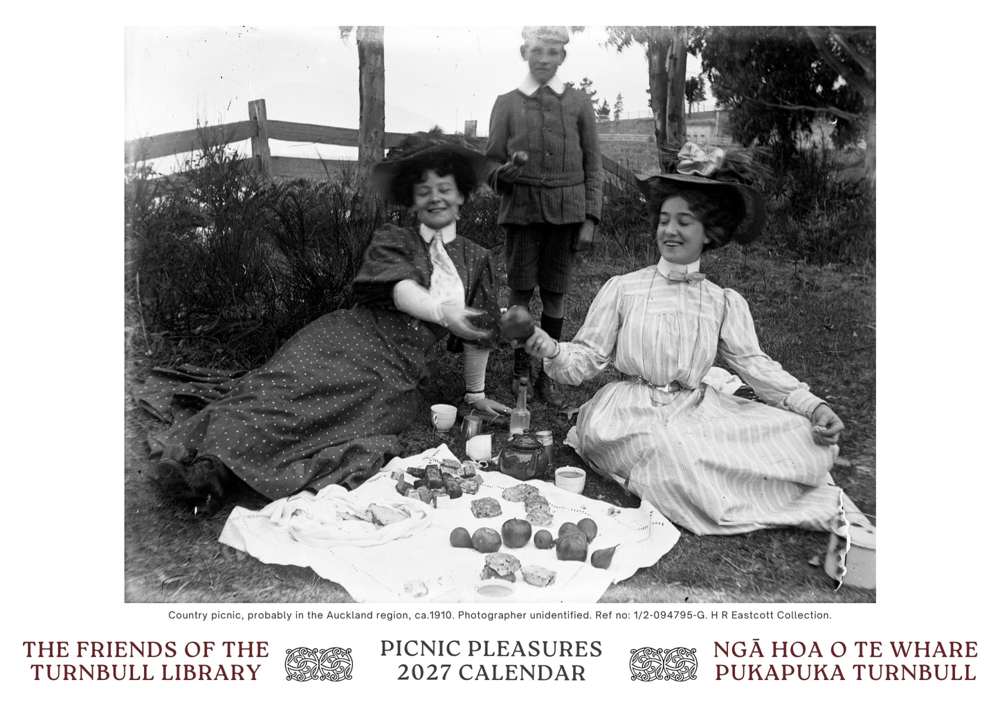 A black-and-white vintage photograph showing three people gathered outdoors for a picnic, with a fence, trees, and lawn in the background. Below the photo is a white border with red text reading 'THE FRIENDS OF THE TURNBULL LIBRARY', 'PICNIC PRESENTS 2027 CALENDAR', and 'NGÒA HOA O TE WHARE PUKAPUKA TURNBULL'.