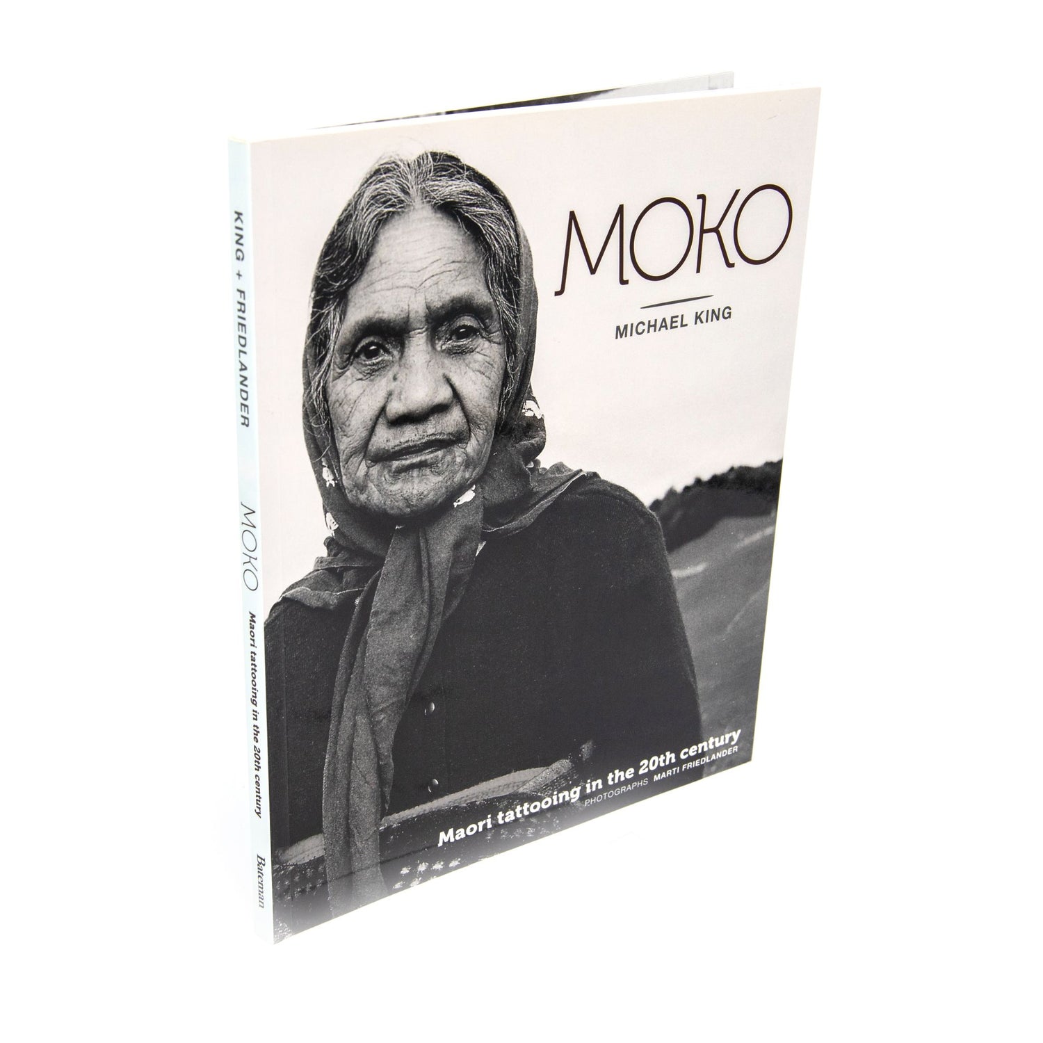 Book cover of 'Moko: Michael King' showing a black and white portrait of a Woman on the front cover. She has a traditional Maori tattoo - a Moko on her jaw. photographed on a clean white background.